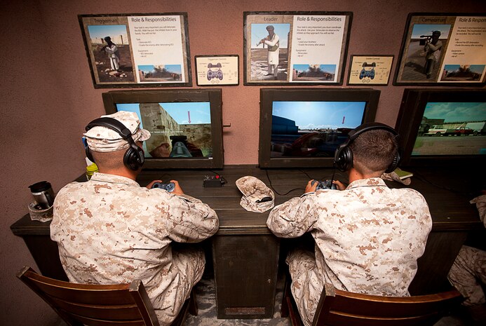 U.S. Marine Pfc. Darrel Wright (left) and Cpl. Dalton Leinen, motor transport operators assigned to Transportation Service Company, Combat Logistics Battalion 3, navigate through a simulated combat scenario while serving as an opposing insurgent force in Marine Corps Base Hawaii?s new Mobile Counter-IED Interactive Trainer, Sept. 18, 2012. The interactive trainer, a series of four trailers decked out with a plethora of high-definition TVs and intricately crafted visual displays, provides Marines a practical, step-by-step education on one of the most significant threats currently facing troops on the ground ? the deadly improvised explosive device. The MCIT helps Marines recognize IEDs and production materials, understand the insurgent mindset and tactical use of IEDs, and how to mitigate their effectiveness and respond to IED events.
