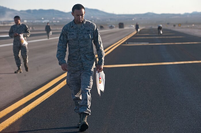 Staff Sgt. Quentin Jackson, 57th Operations Support Squadron air traffic controller, looks for debris on the flightline during a foreign object debris walk Sept. 14, 2012, at Nellis Air Force Base, Nev. Airmen from the 57th Wing conducted the FOD walk to ensure debris from nearby construction of new hangars didn't fall onto the taxiway. FOD checks are conducted to minimize the amount of debris to help ensure the safety of aircraft and personnel. (U.S. Air Force photo by Staff Sgt. Christopher Hubenthal)