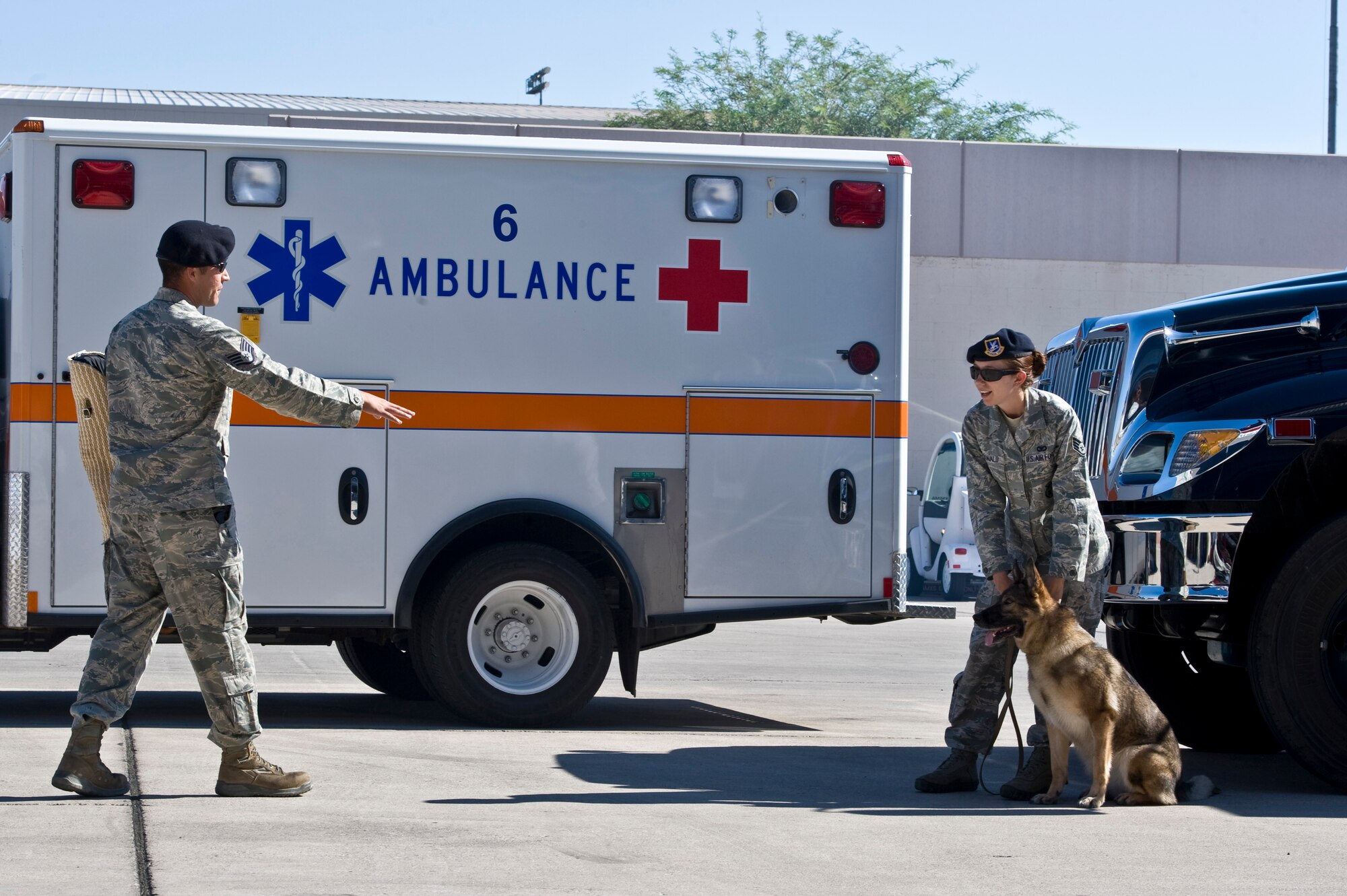 U.S. Air Force Staff Sgt. Alden Dunn, 99th Security Forces Squadron military working dog handler, plays the role of an aggressor while Staff Sgt. Janna McDonald, 99th Security Forces Squadron military working dog handler, handles Chester, military working dog, during Retiree Appreciation Day, Sept. 15, 2012, at Nellis Air Force Base, Nev. Approximately 810 individuals attended the event. (U.S. Air Force photo by Airman 1st Class Matthew Lancaster)