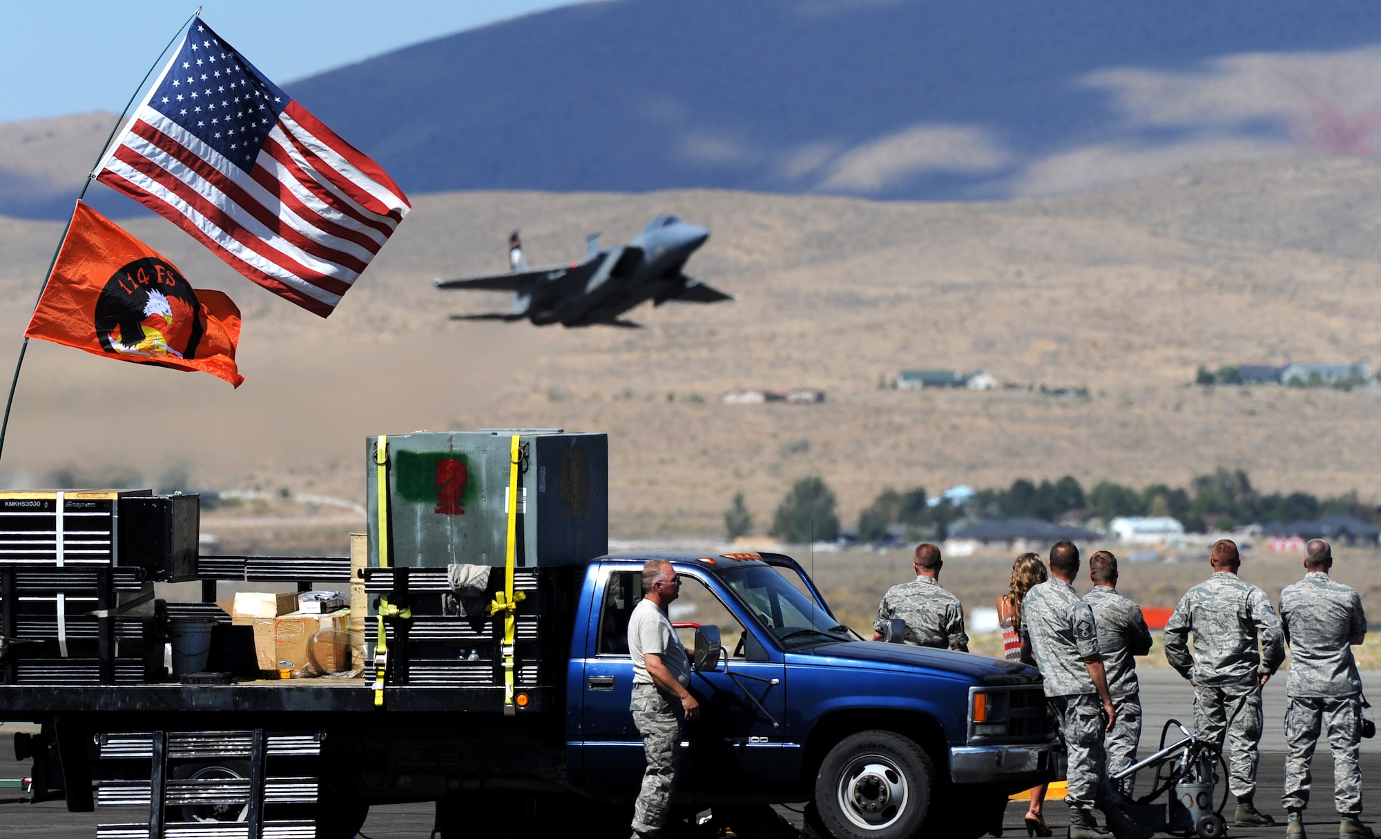 Ground crew from the 114th Fighter Squadron, Oregon Air National Guard, watch their F-15 Eagle fighter aircraft perform a low-level pass during the National Championship Air Races at Stead Airport, Reno, Nev., Sept. 14, 2012. The eagle was one of the hundreds different aircraft at the races. (U.S. Air Force photo by Staff Sgt. Robert M. Trujillo/Released)