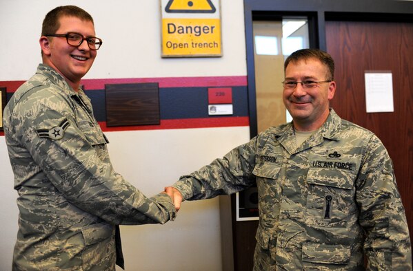 Chief Master Sgt. Kevin Peterson, 28th Bomb Wing command chief, presents his coin to Airman 1st Class Justin Ochs, 28th Aircraft Maintenance Squadron crew chief, in the 34th Bomb Squadron training room at Ellsworth Air Force Base, S.D., Sept. 18, 2012. Ochs was recognized for his positive attitude and outstanding work performance. (U.S. Air Force photo by Airman Ashley J. Woolridge/Released) 