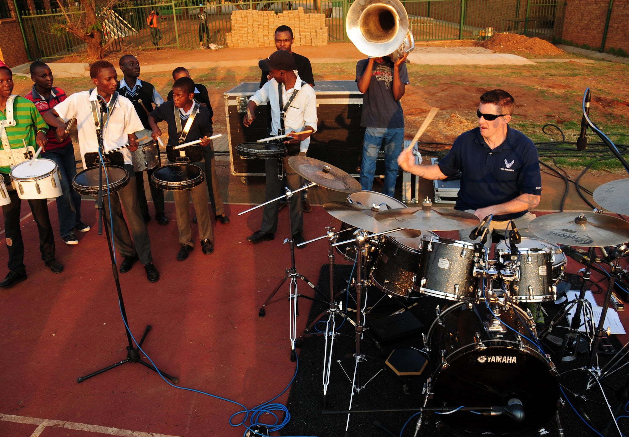 CULLINAN, South Africa -- Staff Sgt. Robert Browning, U. S. Air Forces in Europe rock band percussionist, plays the drums with members of the De Beers PPC Cullinan Field Band drumline during a performance here, Sept. 18. This is the second year Touch ‘n Go has visited the Field Band Foundation and worked with young adults aspiring to become musicians. The foundation is a life skills program which aims to teach young adults to be creative, work together, provides career guidance and discipline, and helps them to empower themselves. (U.S. Air Force photo by Staff Sgt. Debbie Lockhart)