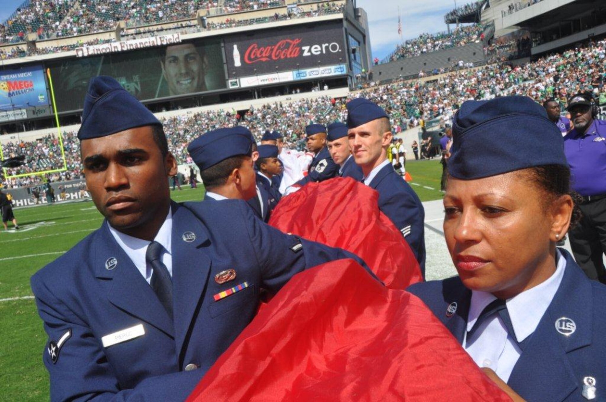 JOINT BASE MCGUIRE-DIX-LAKEHURST, N.J. - Reservist Airman Hassan Pierce of the 514th Force Support Squadron and Chief Master Sgt. Erica Jackson of the 87th Medical Group, here, take part in a pre-game salute to America Sept. 16 at the Philadelphia Eagles' home opener game against the Baltimore Ravens at Lincoln Field in Philadelphia, Pa. It took nearly 150 service members from two major military installations in New Jersey and Pennsylvania to unfurl the American flag that stretched across the entire field.