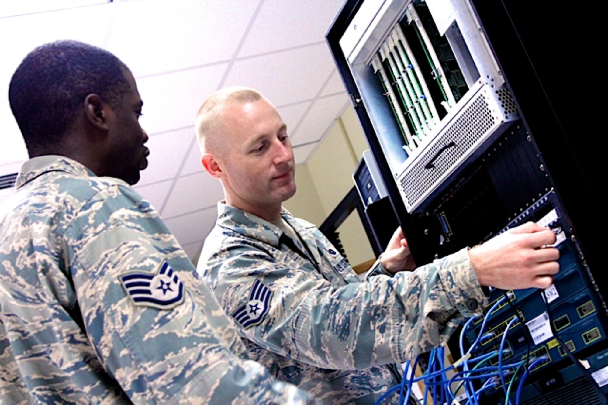 Staff Sgt. Aaron Howard, 338th Training Squadron instructor, and Staff Sgt. Kwanza Lincoln, 338th TRS student, work on switchboard equipment during a cyber transport class at Keesler Air Force Base, Miss. Howard was recently selected to attend Basic Officer Training Sept. 14, 2012,  and will go on to be a combat systems officer.  (Courtesy photo)