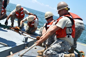 Private 1st Class Brian Green, a watercraft specialist with the 331st Transportation Company, 11th Transportation Battalion, 7th Sustainment Brigade, pulls on a tow line in hopes of connecting two sections of the Trident pier during the preliminary stages of the Joint Logistics-Over-the-Shore exercise, Aug. 16, 2012 at Fort Story, Va. (Courtesy photo)