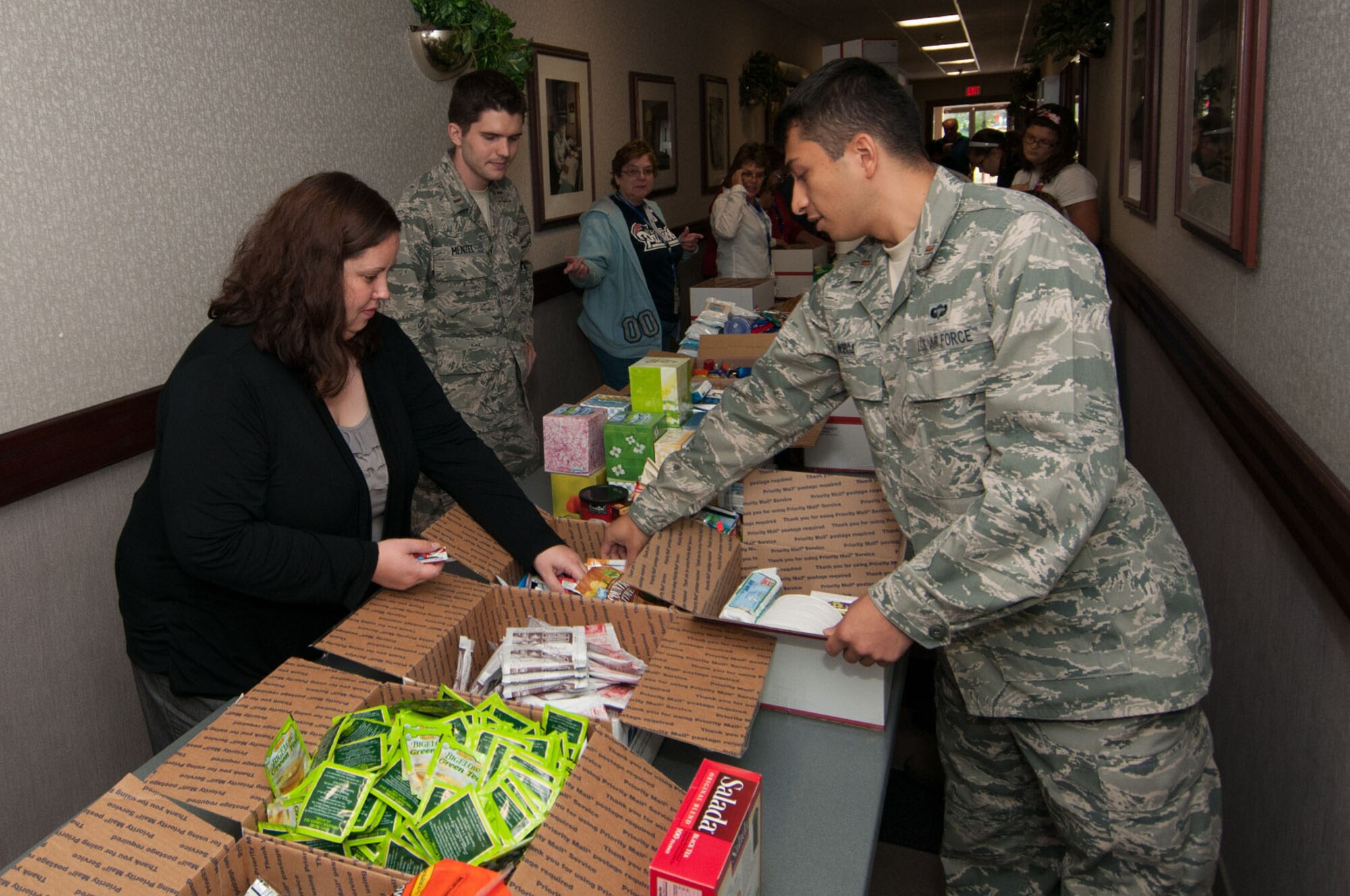 HANSCOM AIR FORCE BASE, Mass. – Second Lt. Javier Noboa (right), with help from many volunteers, place items in troop care packages during the Company Grade Officers Council Troop Care Drive Sept. 12. The organization sponsored the drive to send goods and letters to deployed Airmen from Hanscom. (U.S. Air Force photo by Rick Berry)
