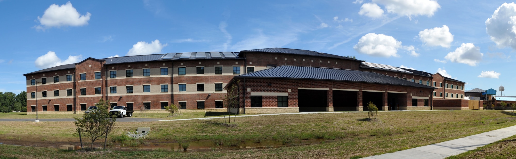 The Advanced Individual Training barracks, seen here on Sept. 14, 2012, accommodates 300 Soldiers assigned to the 128th Aviation Brigade. The building is the first of a four-phase project, and includes various modern amenities, including day rooms, laundry facilities, computer class rooms, supply and arms storage, and lawn maintenance storage. Outside the building, a quarter-mile track, physical training pits and fitness equipment were installed to keep Soldiers physically fit. (U.S. Air Force photo by Staff Sgt. Wesley
Farnsworth/Released)
