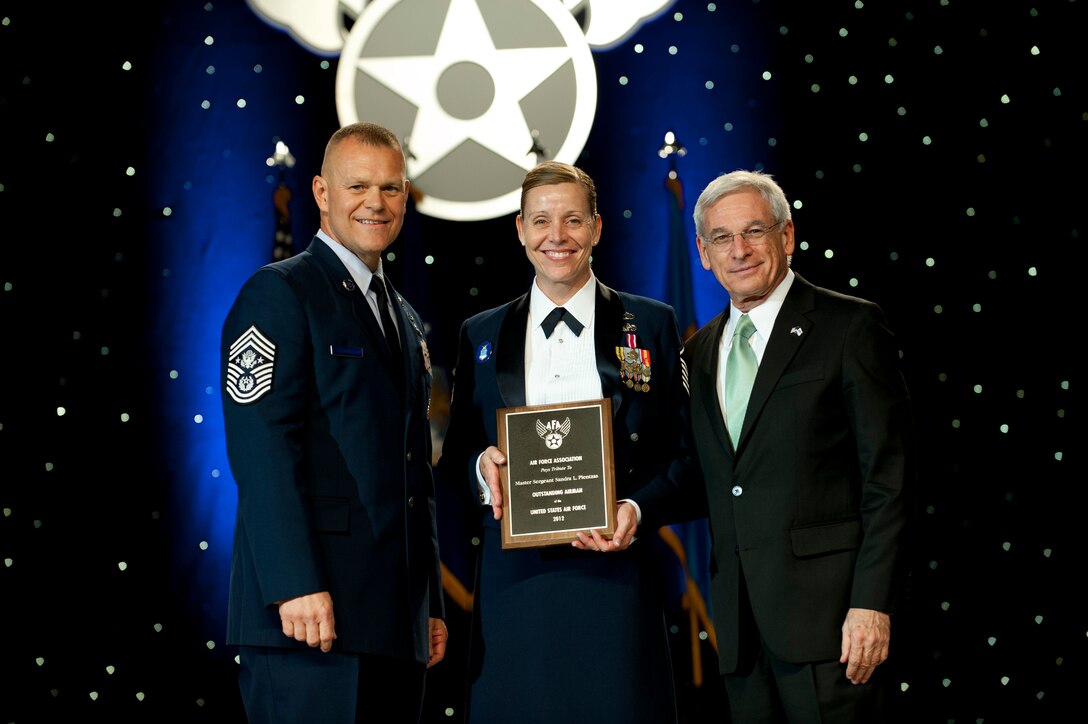 Chief Master Sgt. of the Air Force James Roy, left, and Sandy Schlitt, right, Air Force Association's chairman of the board, present a plaque to Master Sgt. Sandra Plentzas during the 12 Outstanding Airmen of the Year reception and awards dinner in Washington, D.C., Sept. 17, 2012. The recipients were recognized for superior leadership, job performance, community involvement and personal achievements. Plentzas is with the 944th Fighter Wing from Luke Air Force Base, Ariz. (U.S. Air Force photo/Jim Varhegyi)