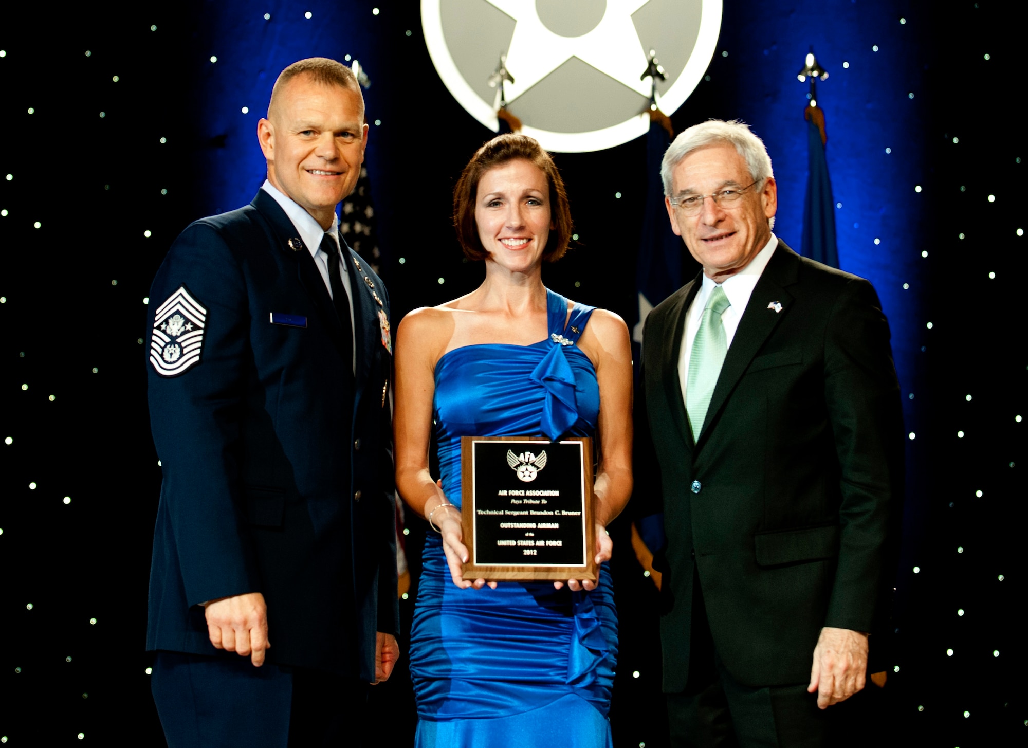 Chief Master Sgt. of the Air Force James Roy, left, and Sandy Schlitt, right, Air Force Association chairman of the board, present a plaque to Sara Bruner, who accepted the award on behalf of her husband Master Sgt. Brandon Bruner, during the 12 Outstanding Airmen of the Year reception and awards dinner in Washington, D.C., Sept. 17, 2012. The recipients were recognized for superior leadership, job performance, community involvement and personal achievements. (U.S. Air Force photo/Jim Varhegyi)