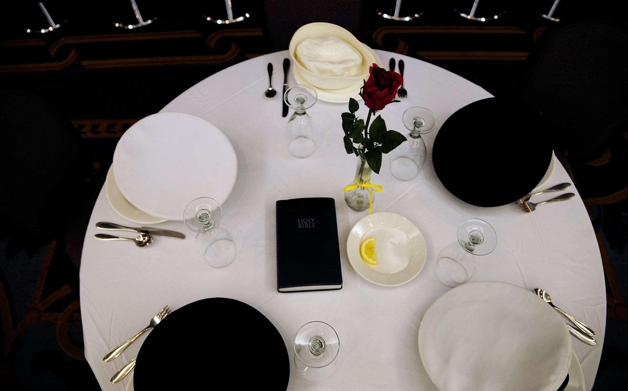 A table sits unoccupied representing U.S. service members who have been prisoners of war or missing-in-action and are now gone, unable to attend, during a POW/MIA breakfast at Whiteman Air Force Base, Mo., Sept. 14. The table is round symbolizing the everlasting concern for those lost; the cloth is white standing for the purity and willingness to answer their country's call to arms; the wineglass is inverted because those gone cannot toast with those attending; the single rose reminds us of families waiting for a loved one to return; the slice of lemon represents the bitter fate of those not home; salt on the table stands for the tears of families who are waiting; and finally, the bible represents strength achieved from faith, helping to sustain those lost from the U.S., founded as one nation under god. (U.S. Air Force photo/Senior Airman Cody H. Ramirez)(RELEASED)