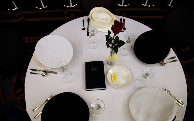 A table sits unoccupied representing U.S. service members who have been prisoners of war or missing-in-action and are now gone, unable to attend, during a POW/MIA breakfast at Whiteman Air Force Base, Mo., Sept. 14. The table is round symbolizing the everlasting concern for those lost; the cloth is white standing for the purity and willingness to answer their country's call to arms; the wineglass is inverted because those gone cannot toast with those attending; the single rose reminds us of families waiting for a loved one to return; the slice of lemon represents the bitter fate of those not home; salt on the table stands for the tears of families who are waiting; and finally, the bible represents strength achieved from faith, helping to sustain those lost from the U.S., founded as one nation under god. (U.S. Air Force photo/Senior Airman Cody H. Ramirez)(RELEASED)