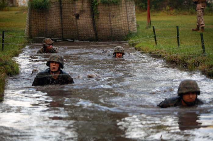 Marines and sailors with Landing Support Company, Combat Logistics Regiment 27, 2nd Marine Logistics Group crawl in the water under a barbed wire obstacle during the endurance course at Battle Skills Training School aboard Camp Lejeune, N.C., Sept. 14, 2012. Servicemembers had to get wet in order to conquer the obstacle and move on with the rest of the three-mile course. 