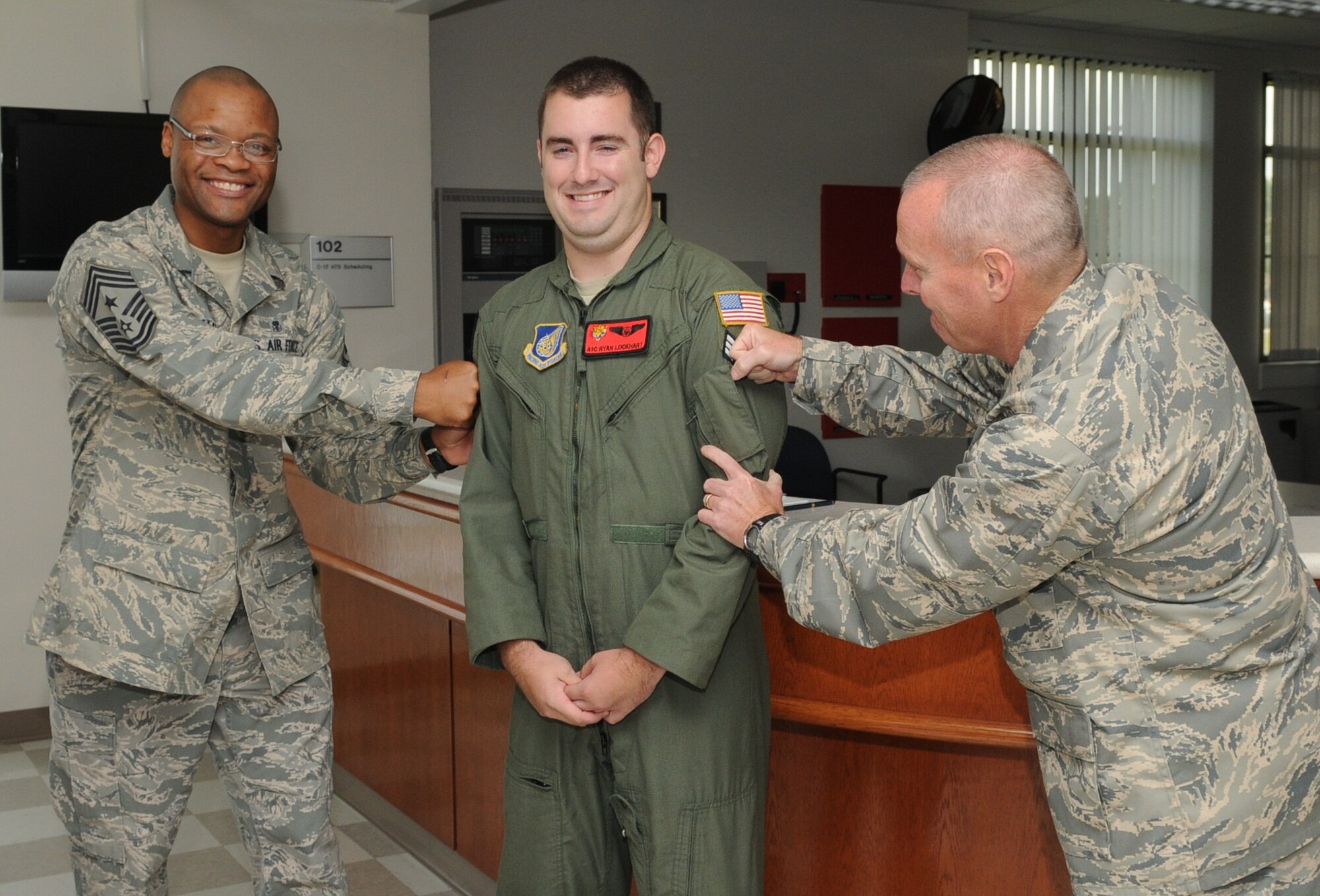 Airman 1st Class Ryan Lockhart, 535th Airlift Squadron is promoted to Senior Airman below-the-zone by Chief Master Sgt. Leslie Bramlett, 15th Wing command chief and Col. Terry Scott, 15th Wing vice commander, at Joint Base Pearl Harbor-Hickam, Hawaii Sept. 19. The BTZ promotion is a competitive early promotion program that allows Airmen to get promoted to Senior Airman six months earlier than they would normally sew on that rank.  (Photo by David D. Underwood, Jr.)