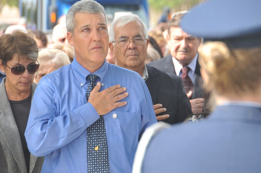 KIRTLAND AFB, N.M. -- Left, Leo David Marquez, son of retired Lt. Gen. Leo Marquez, foreground, and Jim Marquez, the general’s brother, pay respect to the flag during a ceremony here Sept. 17 renaming Bicentennial Park as “Marquez Park.” Marquez died Dec. 30 at age 79. (Photo by Todd Berenger)