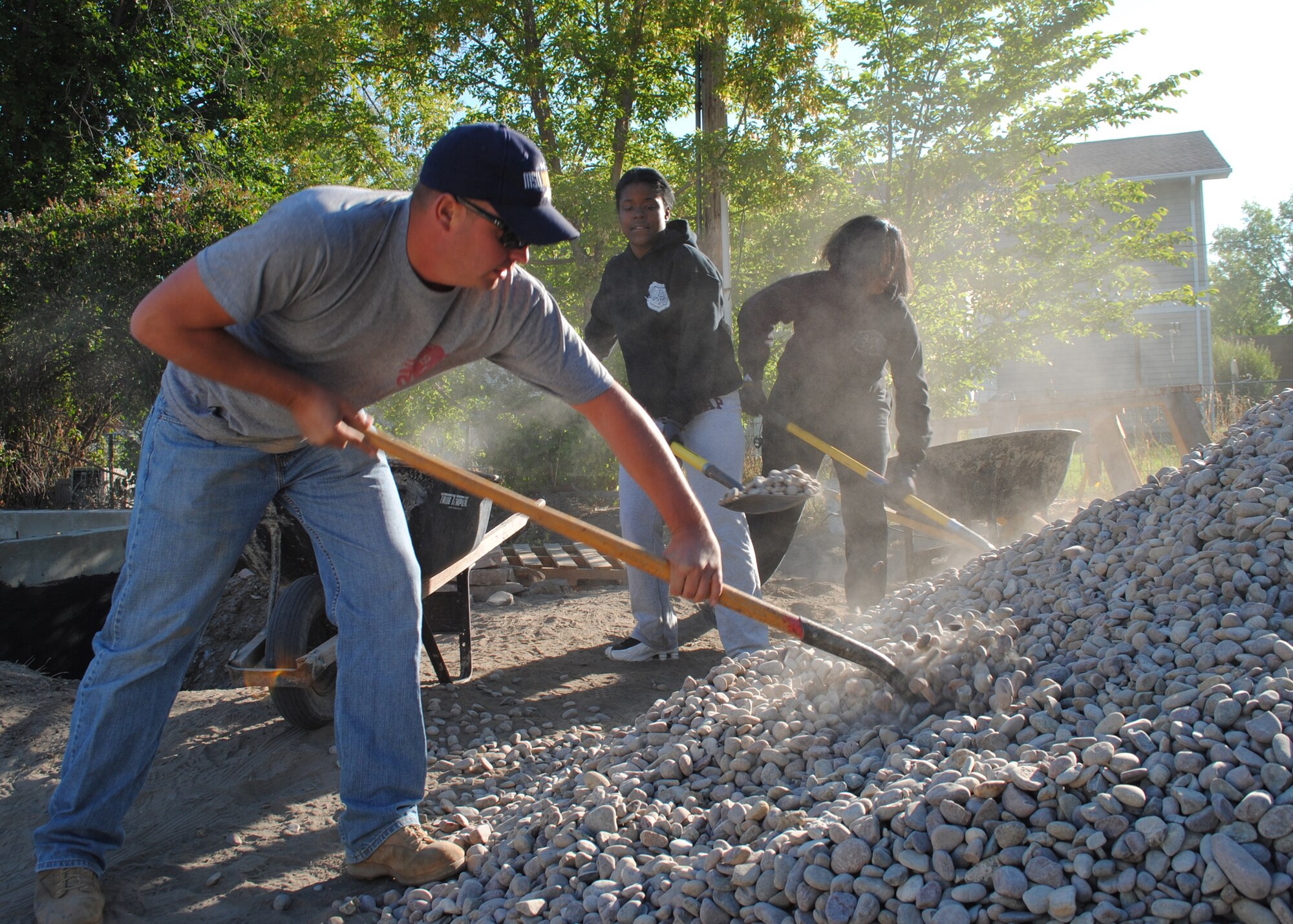 (From left) Staff Sgt. Casey Anderson, 819th RED HORSE Squadron airfields construction team member, and Airmen 1st Class LaMicah Moreland and Shanea Bracy, 341st Logistics Readiness Squadron material control apprentices, work together on shoveling gravel into a wheel barrel during a Habitat for Humanity housing project in Great Falls on Sept. 18. (U.S. Air Force photo/Airman 1st Class Katrina Heikkinen)