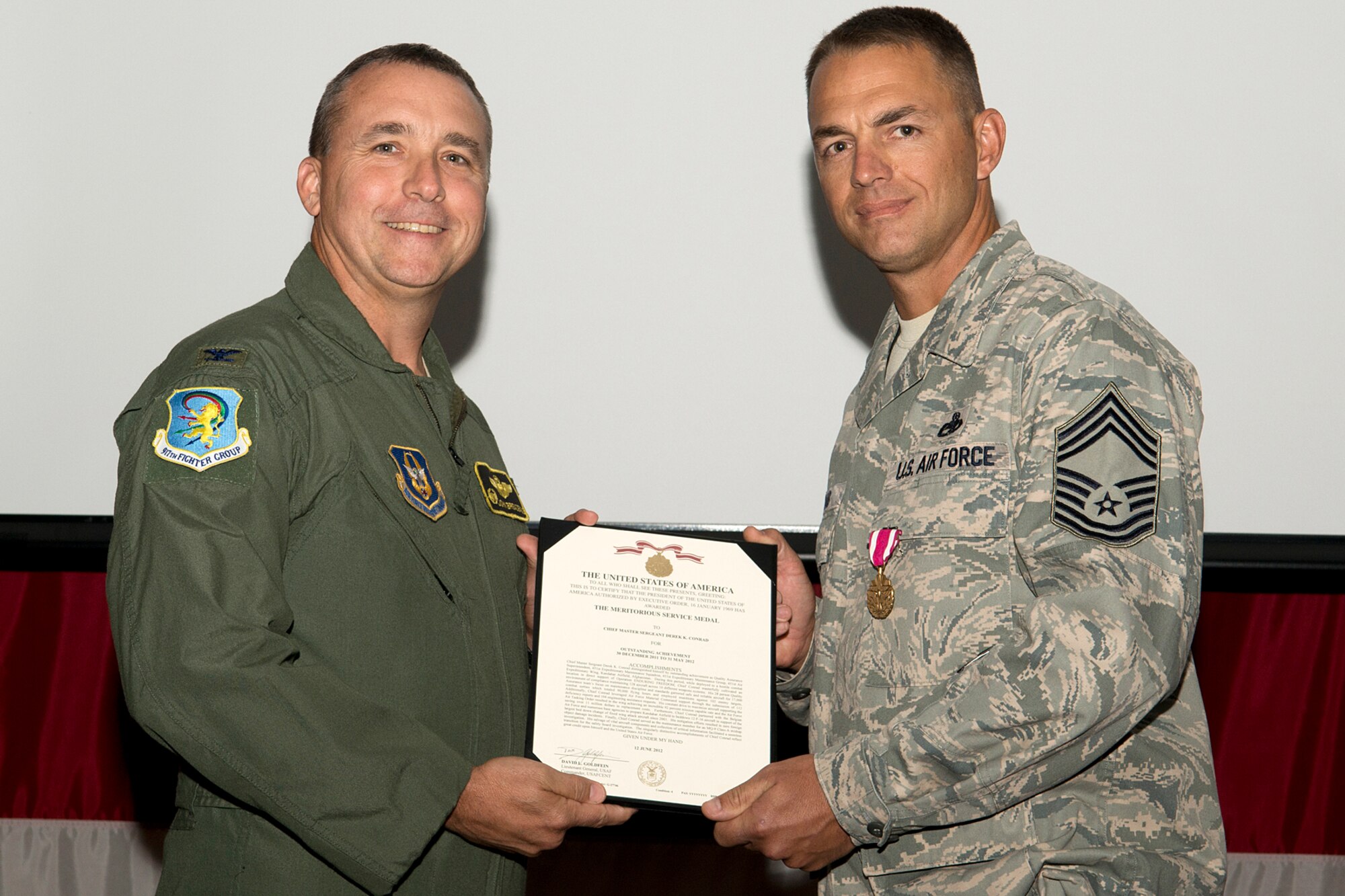 U.S. Air Force Col. John Breazeale, 917th Fighter Group commander, presents the Meritorious Service Medal to Chief Master Sgt. Derek Conrad during a Commander's Call ceremony, Sept. 9, 2012, Barksdale Air Force Base, La. Conrad distinguished himself while deployed to Afghanistan in support of Operation Enduring Freedom. (U.S. Air Force photo by Master Sgt. Greg Steele/Released)