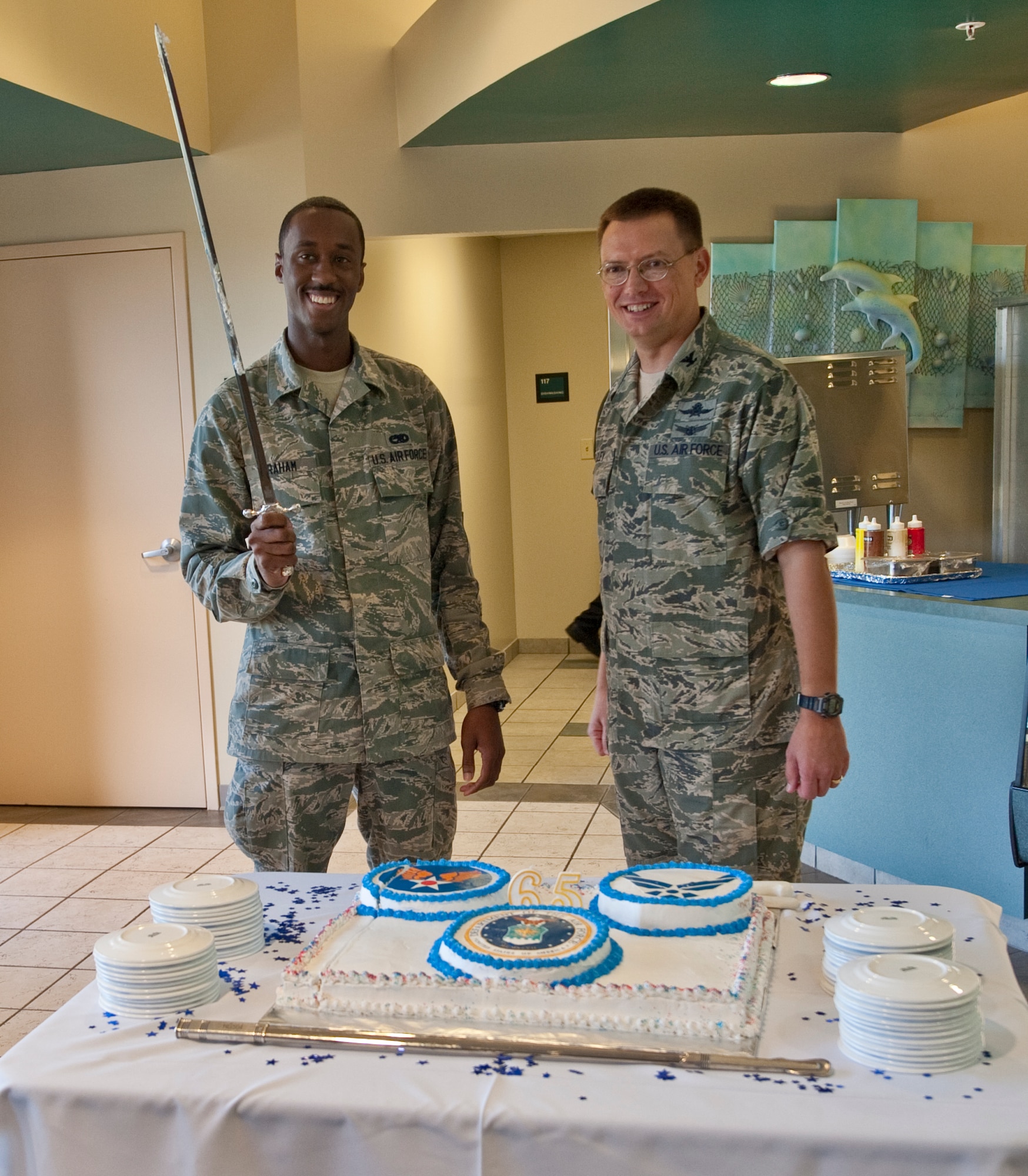 U.S. Air Force Col. Douglas Dudley, commander of 1st Special Operations Mission Support Group, right, and Airman Kemar A. Graham, an armament journeyman of 1st Special Operations Equipment Maintenance Squadron, left, display the saber used to cut a ceremonial cake during the U.S. Air Force’s 65th birthday celebration at the Riptide Dining Facility at Hurlburt Field, Fla., Sept. 18, 2012. As part of Air Force tradition, the most senior- and junior-ranking active-duty Airmen in attendance are selected to slice the cake. (U.S. Air Force Photo/ Airman First Class Nigel Sandridge)