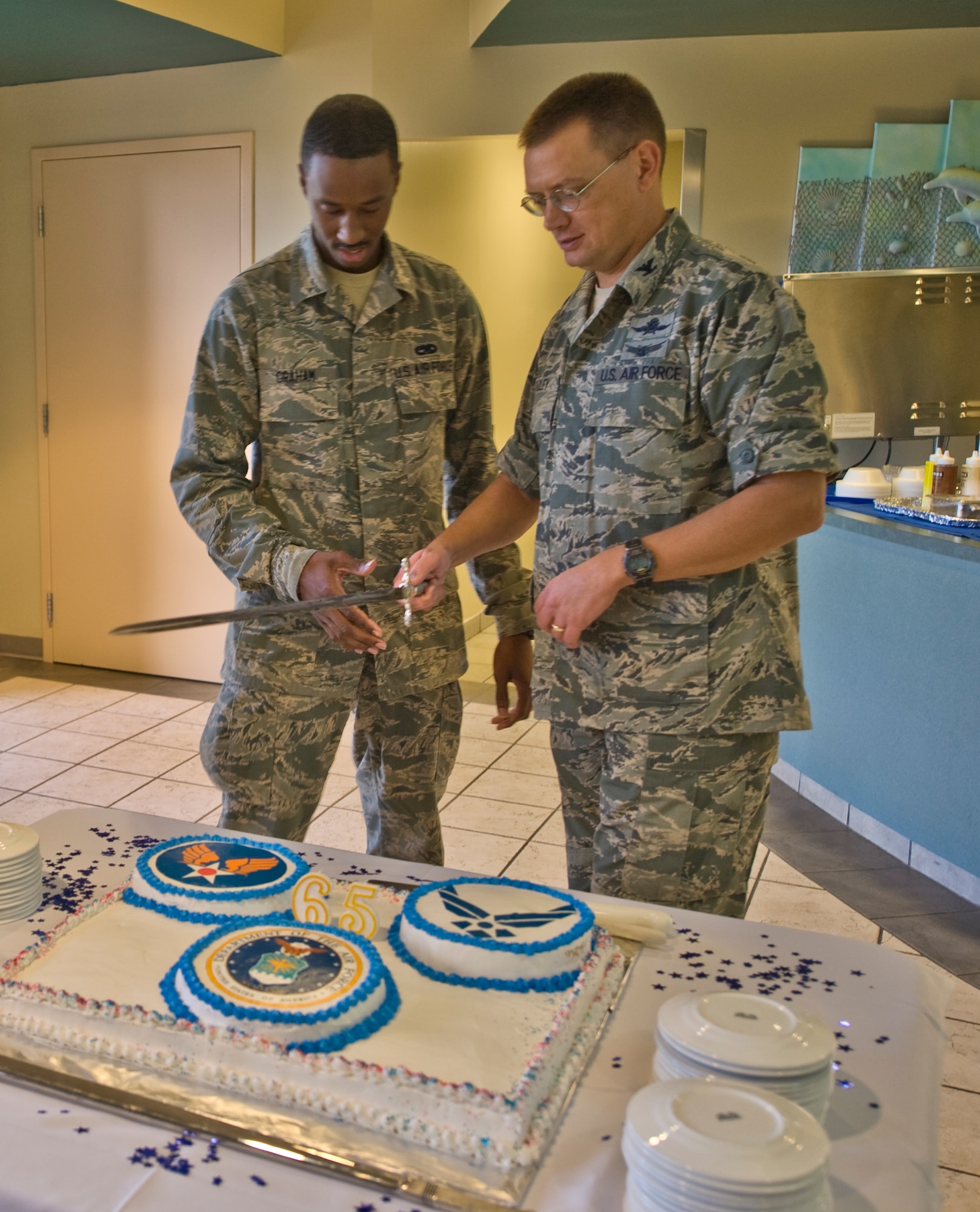 U.S. Air Force Col. Douglas Dudley, commander of 1st Special Operations Mission Support Group, right, and Airman Kemar A. Graham, an armament journeyman of 1st Special Operations Equipment Maintenance Squadron, left, prepare to slice a commemorative cake during the U.S. Air Force’s 65th birthday at the Riptide Dining Facility at Hurlburt Field, Fla., Sept. 18, 2012. Both Dudley and Kemar used the sword to cut the cake as part of Air Force tradition. (U.S. Air Force Photo/ Airman First Class Nigel Sandridge)