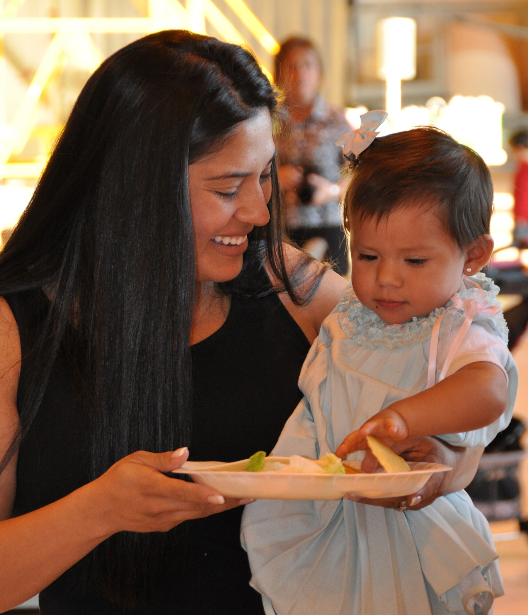 Rita Revilla prepares a plate for her daughter Elena during the Peterson Air Force Base Deployed Family Dinner, sponsored by the 302nd Airlift Wing and its active duty associate unit, the 52nd Airlift Squadron. Approximately 100 family members of deployed personnel from throughout Peterson AFB, Colo. attended the Sept 14, 2012 event held in the 302nd AW aircraft maintenance hangar. Elena's father, Tech. Sgt. Jesus Revilla, is a member of the 21st Civil Engineer Squadron. (U.S. Air Force photo/Tech. Sgt. Daniel Butterfield)