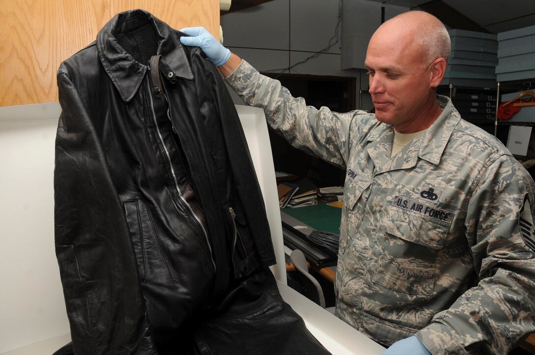 Master Sgt. Eric Grim, 28th Bomb Wing South Dakota Air and Space Museum curator, holds up a World War II era German flight suit on display at the SDA&SM in Box Elder, S.D., Sept. 14, 2012. Part of Grim’s many duties as museum curator is to ensure all artifacts are carefully handled  and properly stored for public viewing. (U.S. Air Force photo by Airman 1st Class Anania Tekurio/Released)