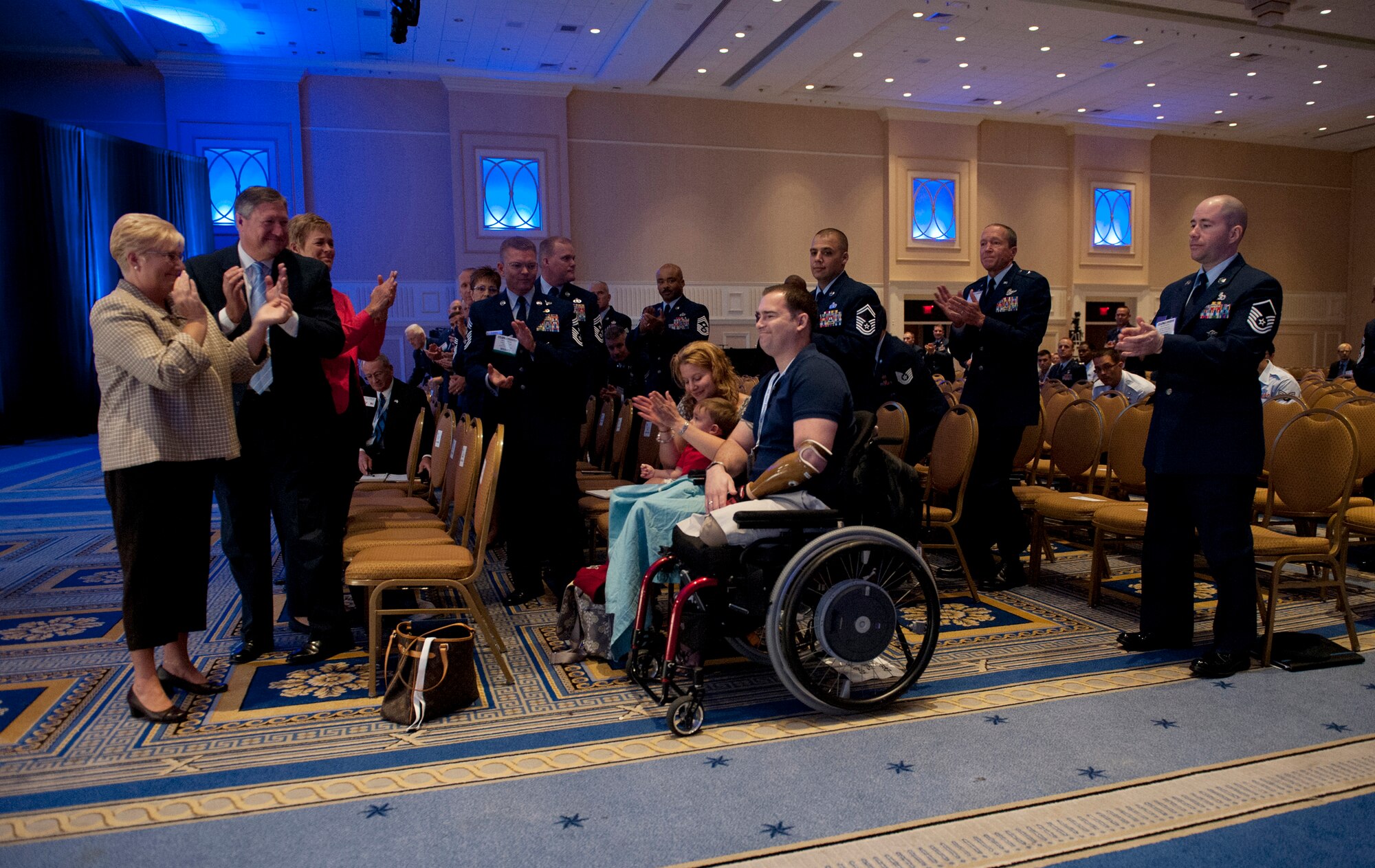 Tech. Sgt. Joe Deslauriers, center, his son, Cameron, and wife, Lisa, are applauded by  the crowd during the enlisted call of Air Force Association's Air and Space Conference and Technology Exposition in Washington, Sept. 19, 2012. Deslauriers, who is an explosives ordnance technician assigned to the 1st Special Operations Civil Engineer Squadron, Hurlburt, Fla., lost both legs in Afghanistan last year. To the left is Paula Roy; wife of CMSAF Roy; Secretary of the Air Force Michael B. Donley and his wife, Gail. (U.S. Air Force photo by Val Gempis)