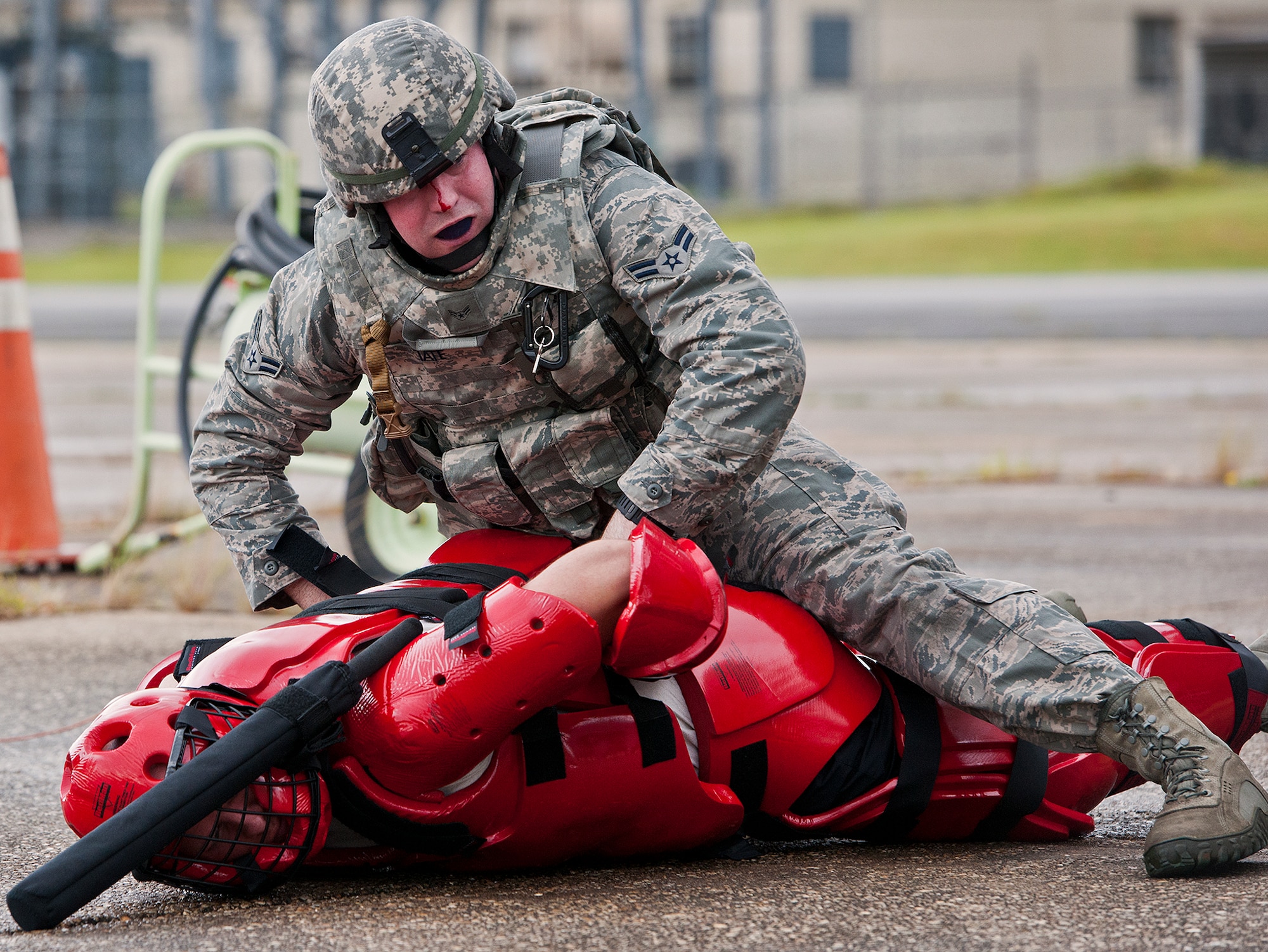Airman 1st Class Kirk Tate, of the 319th Security Forces Squadron, secures an enemy combatant during a Fly Away Security Team training session Sept. 17 at Eglin Air Force Base, Fla. The course, taught by 96th Ground Combat Training Squadron instructors, brought together security forces Airmen from McConnell AFB, Kansas and Grand Forks AFB, N.D., to learn how to protect aircraft and handle a potential hostile situation. Tate was cut when the night vision goggle mount on his helmet hit the bridge of his nose while subduing a simulated enemy.  (US. Air Force photo/Samuel King Jr.)