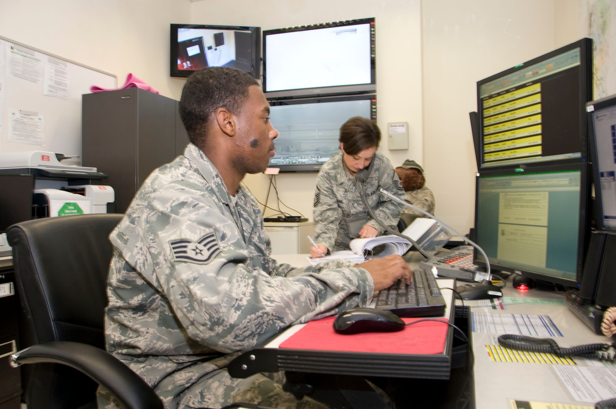Master Sgt. Lesley Perrine, 379th Air Expeditionary Wing Command Post superintendent, talks with Combined Force Air Component Commander's Watch Cell while coordinating a higher headquarters report for an ongoing situation. Staff Sgt. Dennis Patterson, 379th AEW CP controller, tracks commander's locations and logs daily events. The command post acts as the eyes and ears of the commander, and is the conduit in charge of keeping organizations connected, coordinating base functions to include first responder actions, weather alerts and aircraft activity while keeping all agencies on the same page 24 hours a day. Perrine is deployed from Spangdahlem Air Base, Germany, and Patterson is deployed from Yakota Air Base, Japan. (U.S. Air Force photo/Senior Airman Bryan Swink)