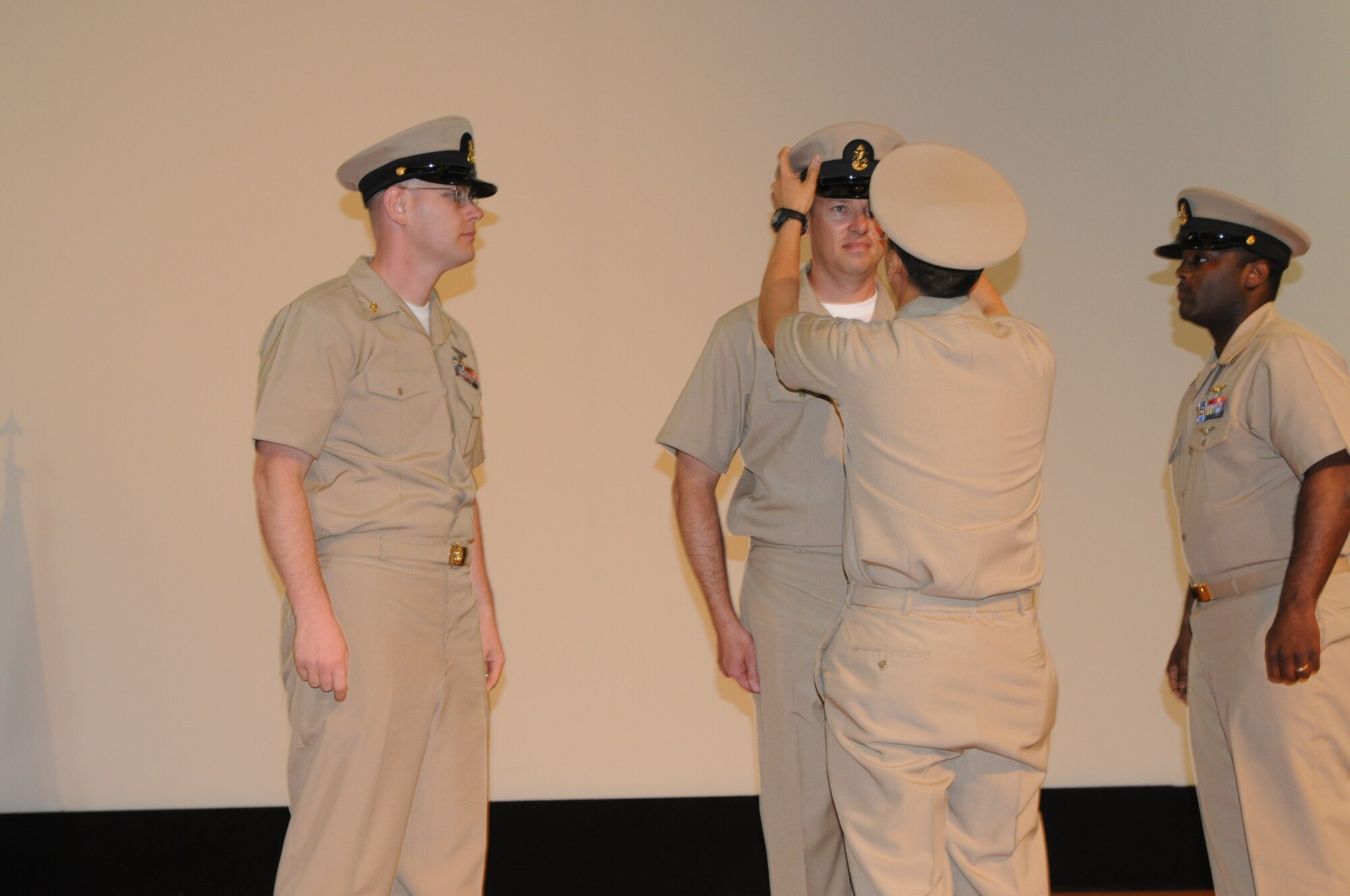U.S. Navy Chief Petty Officer (middle) Anh Le places the Chief?s Combo Cover on Chief Petty Officer Jason Lacey after pinning the new rank. The placing of the Chief?s Combo Cover is a time honored tradition that is performed by a genuine Chief Petty Officer. Members from Class 119 are the first Chief Petty Officer?s to be pinned here at the 379th Air Expeditionary Wing during the inaugural Chief Petty Officer Pinning Ceremony in Southwest Asia, September 14, 2012. (U.S. Air Force photo/Capt. Craig Carper)