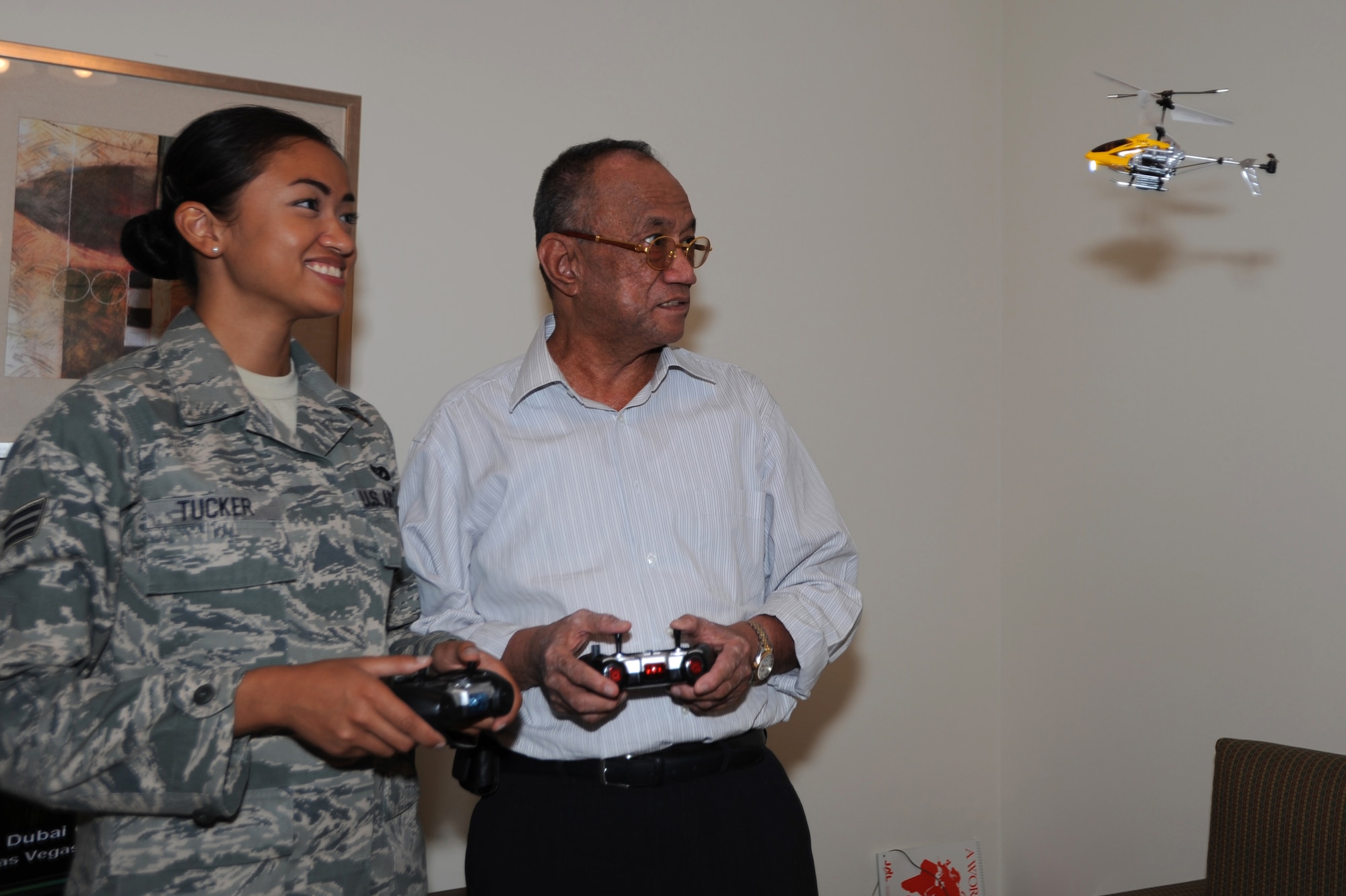U.S. Air Force Senior Airman Joyce Tucker, 379th Expeditionary Civil Engineer Squadron construction site manager, maneuvers a remote control helicopter with the help of her grandfather, Tito Pagdanganan. Tucker and Pagdanganan met for the first time in 22 years during Tucker?s deployment to Southwest Asia, September, 5, 2012. (U.S. Air Force photo/Staff Sgt. Sheila deVera)