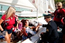 U.S. Army Sgt. Jacob Turner hands the remains of Louis “Papa Lou” Foster, a retired Air Force master sergeant, and creator of Hickam Harbor, to Connie Guthrie, Papa Lou’s daughter to set sail on a ceremonial voyage around Hickam Harbor, Sept. 1 at Joint Base Pearl Harbor-Hickam, Hawaii. Founder of the Wets Hens Foster is best known for his sailing skills. He died in his hometown of Eagle Point, Ore., at the age of 90. (U.S Air Force photo/Staff Sgt. Mike Meares)