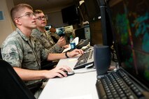Airman 1st Class Clayton Bradley gets on the job training from Senior Airman Kyle Apholz, 17th Operational Weather Squadron, Aug. 23 at the Pacific Air Forces Headquarters, Joint Base Pearl Harbor-Hickam, Hawaii. The 17th OWS recently completed a standardization and evaluation program for weather operations, or SEPWO, inspection where they scored 214 out of a possible 215 points, for a 99.53 percent passing score. Members of the squadron had to pay up on a shaving bet when they scored higher than 97 percent, including more than 75 years of continuous mustache growth. (U.S. Air Force photo/Staff Sgt. Mike Meares)