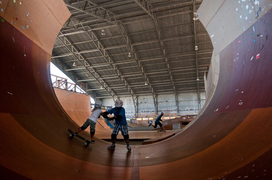 Sean Woodward, 13, helps his sister, Lindsey Hawk, 5, skate on the three-quarter pipe ramp Aug. 22 at Joint Base Pearl Harbor Hickam, Hawaii. The converted hangar is the only indoor wooden facility on all the Hawaiian Islands. It also boasts the only wooden keyhole bowls, or empty swimming pool shaped ramps, on Oahu. In addition, it has a 15,000 square foot street course, multiple mini ramps, 12-foot vertical ramp with a 14-foot tombstone connected to a saddle and three-quarter pipe. (U.S. Air Force photo/Staff Sgt. Mike Meares)
