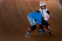 Sean Woodward, 13, helps his sister, Lindsey Hawk, 5, get the correct stance on a skateboard while on the 12-foot vertical ramp Aug. 22 at Joint Base Pearl Harbor Hickam, Hawaii. The converted hangar is the only indoor wooden facility on all the Hawaiian Islands. It also boasts the only wooden keyhole bowls, or empty swimming pool shaped ramps, on Oahu. In addition, it has a 15,000 square foot street course, multiple mini ramps, 12-foot vertical ramp with a 14-foot tombstone connected to a saddle and three-quarter pipe. (U.S. Air Force photo/Staff Sgt. Mike Meares)