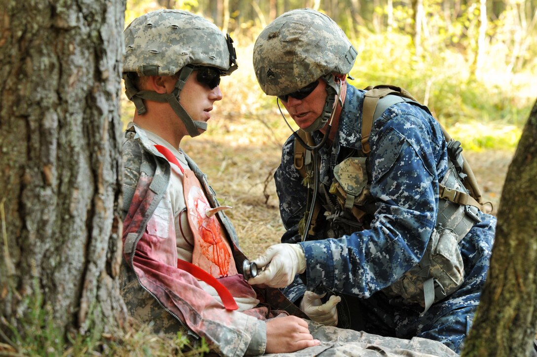 U.S. Navy Petty Officer 2nd Class Sean Miller, right, assesses a simulated casualty at a combat testing lane at U.S. Army Europe's Expert Field Medical Badge Competition in Grafenwoehr, Germany, Sept. 18, 2012. 