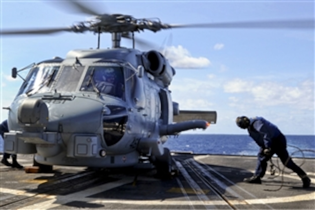 U.S. Navy Seaman Austin Diberardino removes chocks and chains from an MH-60R Seahawk helicopter assigned to Helicopter Marine Strike Squadron 46 during flight quarters aboard the guided missile cruiser USS Gettysburg en route to Scotland, Sept. 19, 2012. The Gettysburg is scheduled to take part in Exercise Joint Warrior, which seeks to improve interoperability between allied navies.