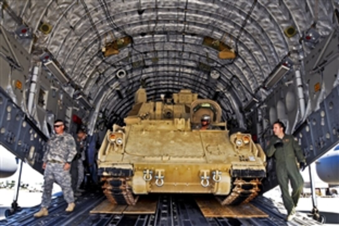 Army Sgt. Woody, center, backs his M32 Bradley fighting vehicle into the cargo bay aboard a 105th Airlift Wing C-17 Globemaster III after receiving instructions from Air Force Master Sgt. Krystopher Schwandt, right, on Stewart Air National Guard Base in Newburgh, N.Y., Sept. 19, 2012. Woody is assigned to the 5th Squadron, 15th Cavalry Regiment, and Schwandt, a loadmaster, is assigned to the assigned to the 137th Airlift Squadron.