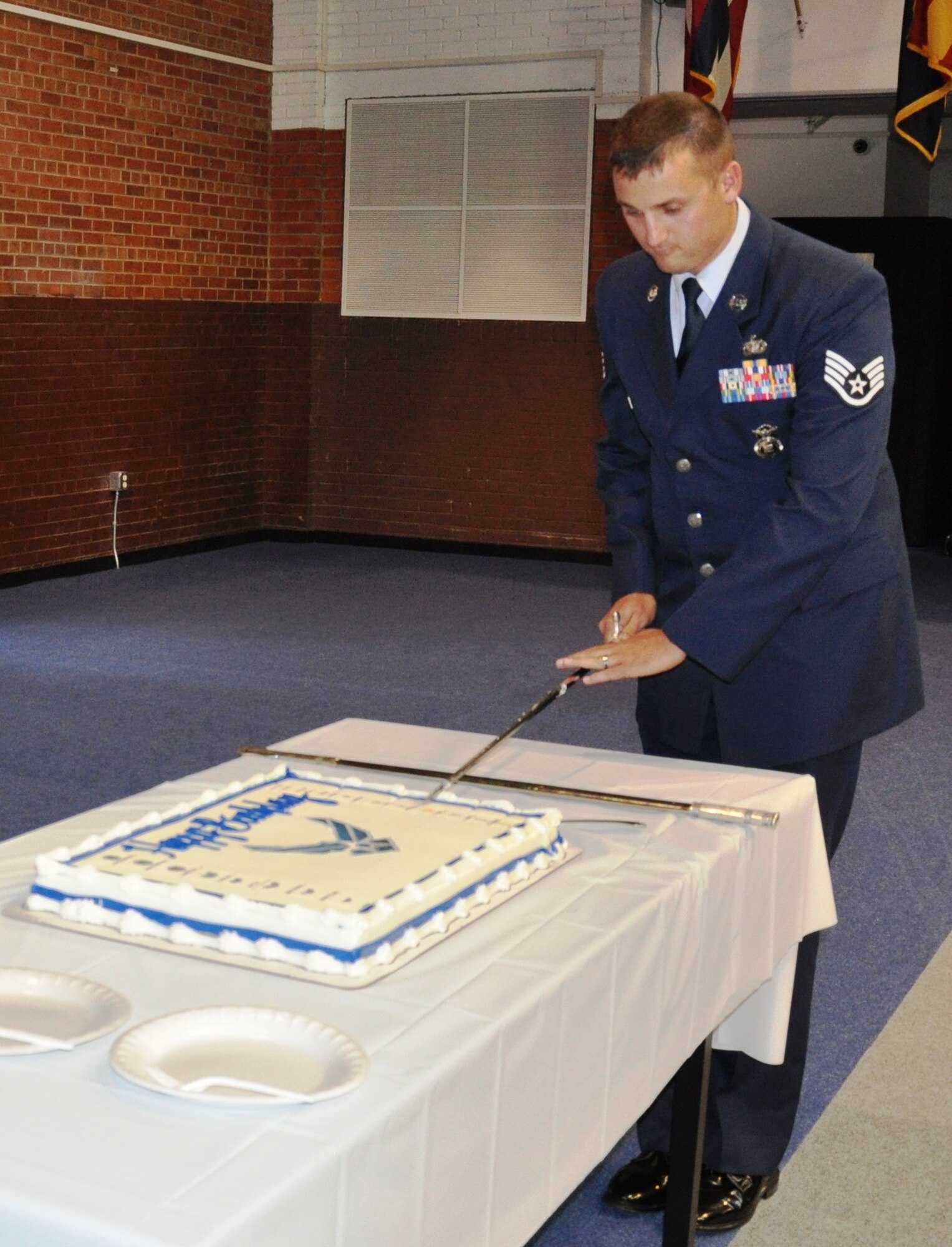 Staff Sgt. Josh Williams, 90th Security Support Squadron and Base Honor Guard member, ceremoniously cuts the Air Force Birthday Cake during the celebration of the Air Force’s 65th birthday at the Fall Hall Community Center on F. E. Warren Air Force Base, Wyo., Sept. 16. As is tradition, the youngest enlisted Airman, Airman John Baker, 90th Communications Squadron; the longest-serving civilian, Elaine Hart, 90th Missile Wing Legal Office; and Col. George Farfour, 90th Missile Wing vice commander,  receive the first pieces of the cake to commemorate the Air Force Birthday. (U.S. Air Force photo/Staff Sgt. Torri Savarese) 