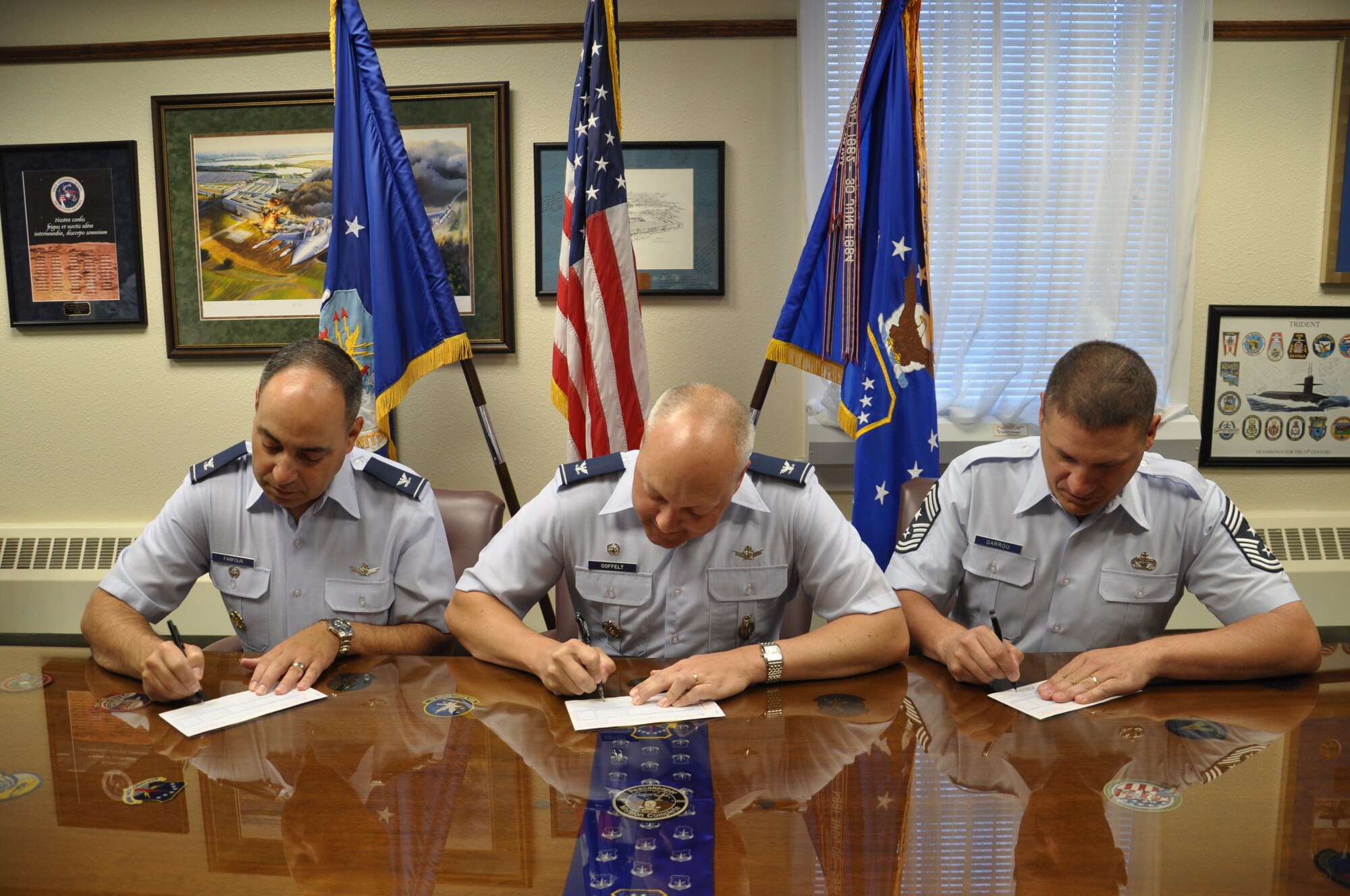 Col. Christopher Coffelt, 90th Missile Wing commander; Col. George Farfour, 90th MW vice commander; and Chief Master Sgt. Michael Garrou, 90th MW command chief, sign their donation forms for the Combined Federal Campaign, Sept. 10. The campaign officially kicks off Oct. 1, and Warren Airmen can donate to more than 4,000 local and national charities. (U.S. Air Force photo/Senior Airman Dan Gage)