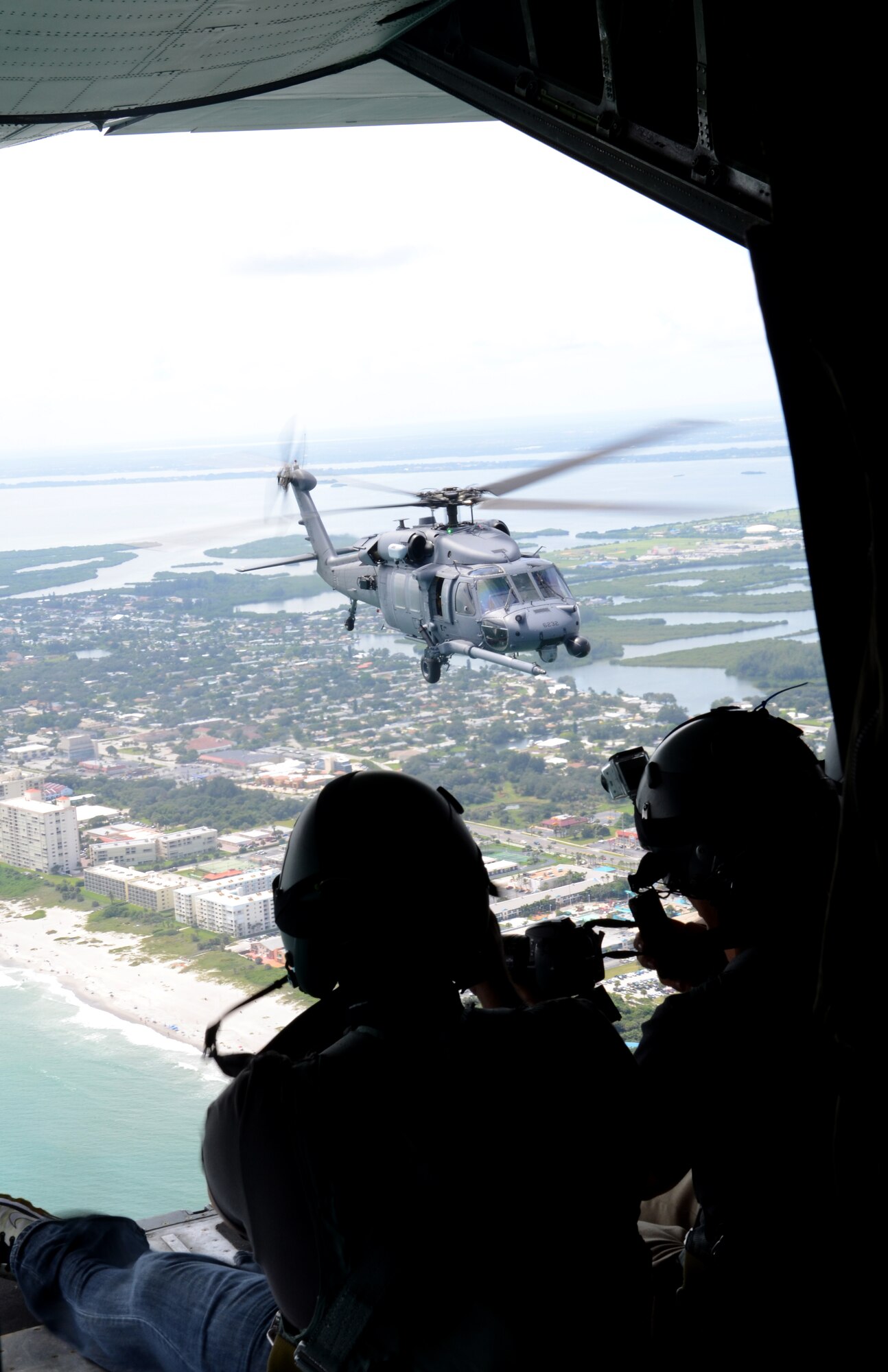 Local media, on the ramp of an HC-130P/N King, photograph an HH-60G Pave Hawk rescue helicopter as Rescue Airmen simulate a mid-air refuel. 920th Rescue Wing Airmen based at Patrick Air Force Base, Fla., are scheduled to perform during the 2012 Cocoa Beach Air Show Sept. 22 and 23. (U.S. Air Force photo/Senior Airman Natasha Dowridge)