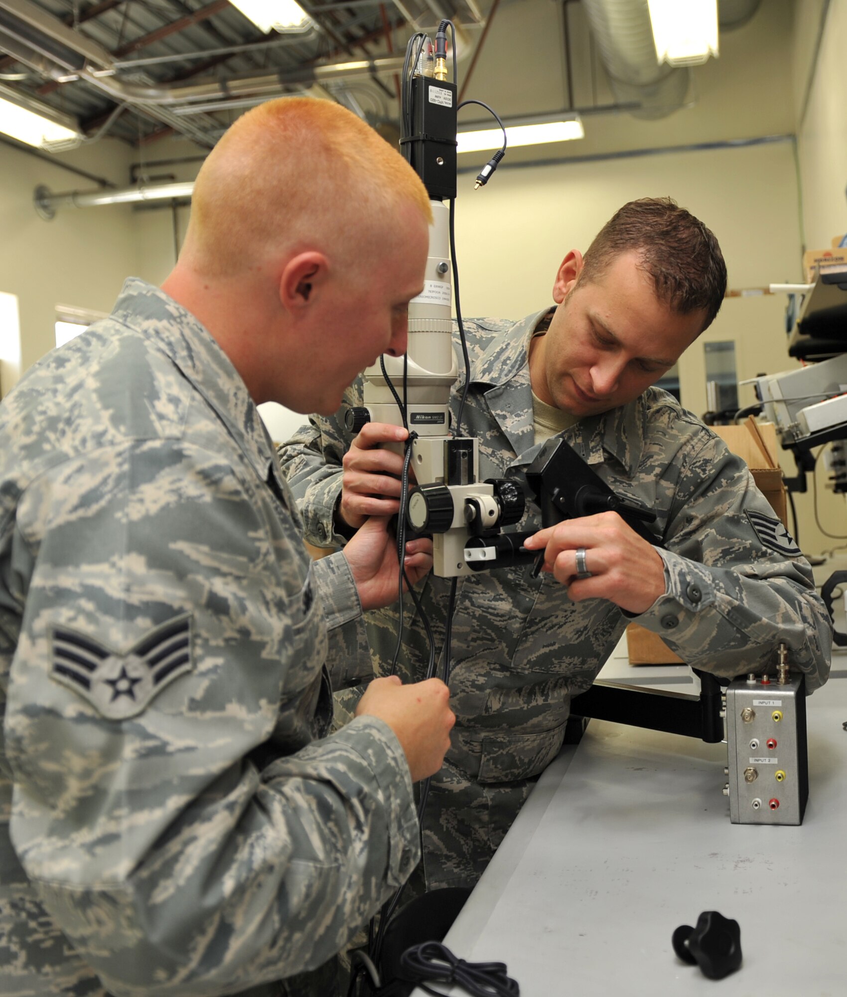 U.S. Air Force Staff Sgt. Thomas Beaudet, 366th Air Force Repair Enhancement Program circuit card technician and Senior Airman Justin Sims, 366th AFREP supply journeyman, assemble a microscope Aug. 28, 2012, at Mountain Home Air Force Base, Idaho. The microscope displays images onto a TV to enable multiple people to view the item, and is mainly used for training purposes. (U.S. Air Force photo/Airman 1st Class Heather Hayward)