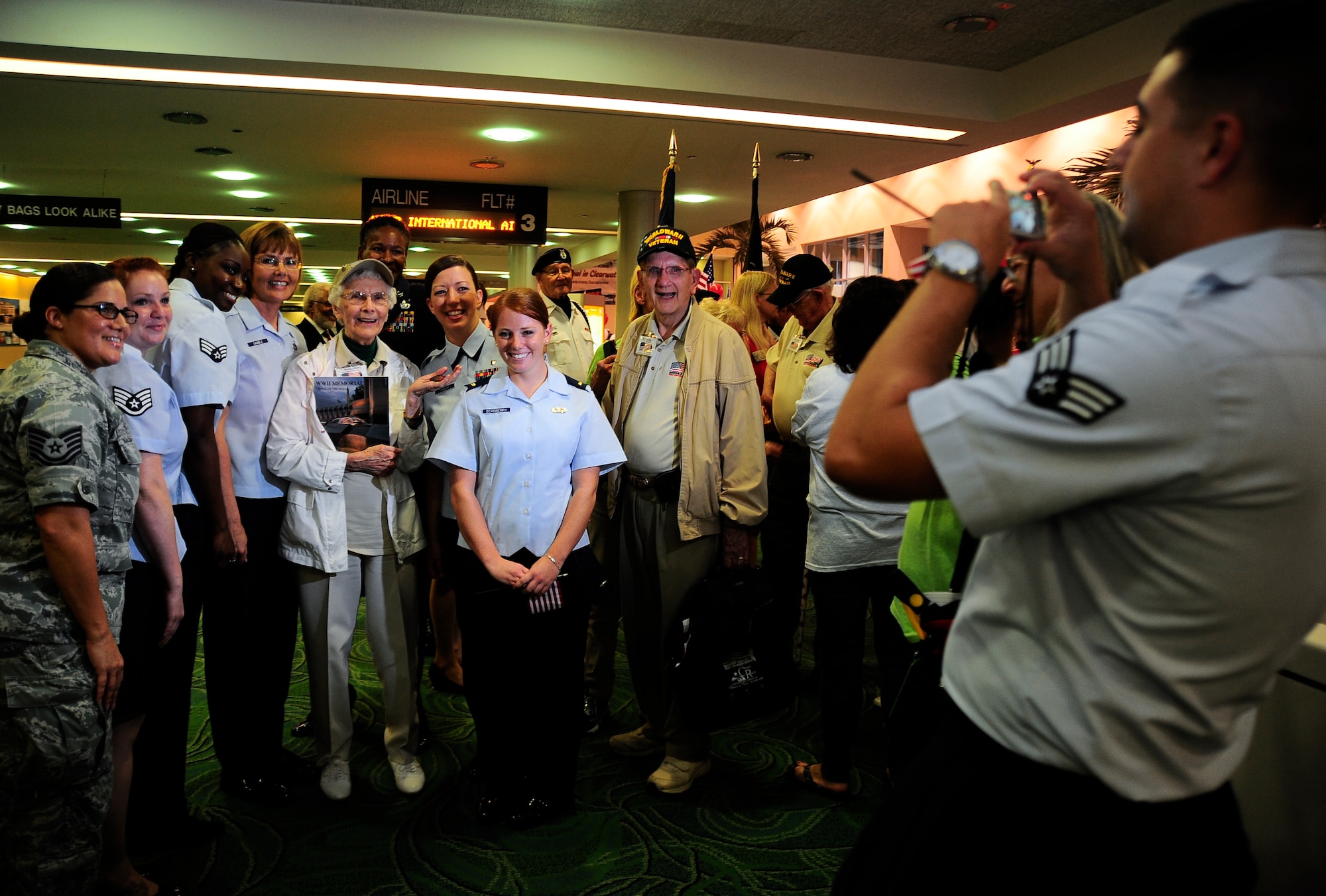 Senior Airman Adam Gilreath, 6th Contracting Squadron, takes a photograph of World War II veterans with Airmen from MacDill Air Force Base, Sept. 12, 2012. More than 300 people greeted the WWII veterans honored during the seventh Honor Flight of West Central Florida at the St Petersburg Clearwater International Airport, Fla. (U.S. Air Force photo by Staff Sgt. Angela Ruiz)