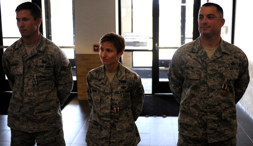 Tech. Sgt. Claire Beck (center), Air Force Financial Services Center remissions branch chief, stands with Senior Airman Thomas Archer (left), AFFSC overseas relocations technician, and Senior Master Sgt. Brian Evanczik (right), AFFSC superintendent, during an awards ceremony for the remaining Airmen of the AFFSC in the AFFSC main lobby on Ellsworth Air Force Base, S.D., Sept. 19, 2012. As part of Air Force-wide  efficiency efforts tied to budget restructuring, military members who formerly handled military pay functions at the AFFSC will be returning to individual bases to serve their customers. (U.S. Air Force photo by Airman Ashley J. Woolridge/Released)
