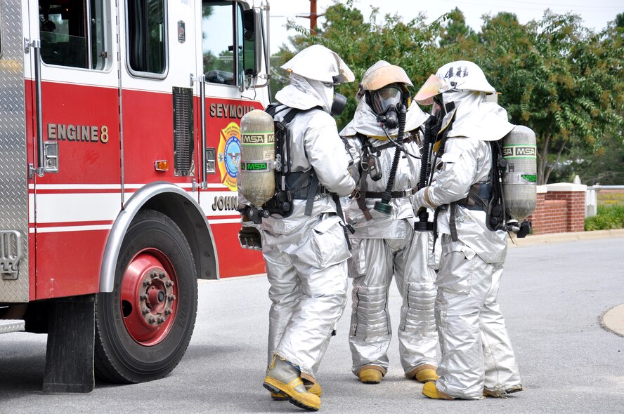 Firefighters from the 4th Civil Engineer Squadron discuss their plan of action for entering a building after a simulated attack during Phase II of Operational Readiness Exercise Coronet Warrior 12-04 at a simulated deployed location on Seymour Johnson Air Force Base, N.C., Sept. 20, 2012. Evaluators tested the wing's ability to rapidly deploy, survive and operate under simulated conventional, chemical and biological conditions. (U.S. Air Force photo/Staff Sgt. Courtney Richardson/Released)
