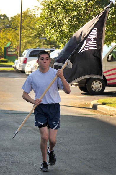 Airman 1st Class Jeremy Pablano, 99th Airlift Squadron resource management apprentice, carries the prisoner of war flag to a POW Remembrance Ceremony, following a Vigil Run at Joint Base Andrews, Md. The run began 24 hours prior to the Sept. 21 ceremony with more than two hundred runners carrying the POW flag overnight. (U.S. Air Force photo by Senior Airman Steele C. G. Britton)  