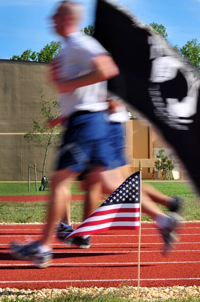 Runners carry the prisoner of war flag to honor those missing in action through conflicts of foreign war worldwide during a Vigil Run Sept. 20 at Joint Base Andrews, Md. The 24-hour run was divided between more than two hundred supporters who held the flag to support those who are "never forgotten." (U.S. Air Force photo by Senior Airman Steele C. G. Britton)