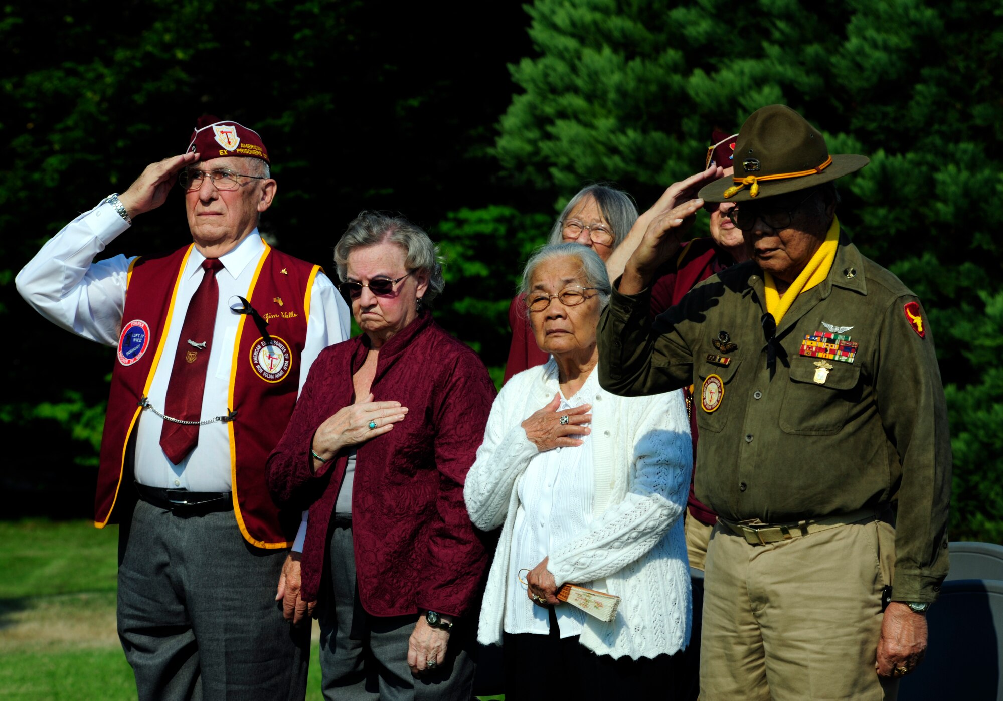 Former Prisoners of War, James Wells (left) and Dan Figuracion (right) and their spouses, show respect during the playing of the national anthem at the Sept. 17, 2012 POW/MIA remembrance ceremony at Memorial Grove park, Joint Base Lewis-McChord, Wash. Both members are former POWs from World War II.  (U.S. Air Force photo/Master Sgt. Todd Wivell)