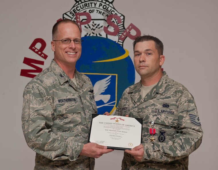 Col. Mark Weatherington, 28th Bomb Wing commander, presents the Bronze Star to Tech. Sgt. Dale Spencer II, 28th Security Forces Squadron flight chief, at Ellsworth Air Force Base, S.D., Sept. 19, 2012. Spencer distinguished himself while leading a 13-person security element in ground combat operations against enemy forces at Kandahar Airfield, Afghanistan from April 10, 2012 to Oct. 12, 2010. (U.S. Air Force photo by Airman 1st Class Zachary Hada/Released)