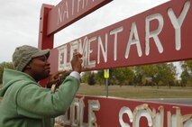CeeCee Long, a Grand Forks Air Force Base parent, removes tape from the Nathan Twining Elementary and Middle School sign after applying a fresh coat of paint to the lettering as part of Twining and Eielson’s Fall Beautification Day. Other volunteers performed tasks such as gardening, raking dead grass and leaves, and edging sidewalks. (U.S. Air Force photo/Senior Airman Susan L. Davis)