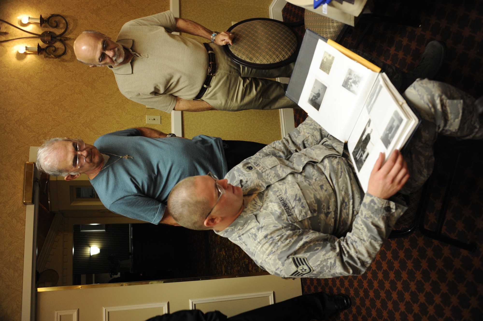 Staff Sgt. Benjamin Eisenhart, a 87th Security Forces Squadron military working dog handler, reviews an album of photos and documents compiled by Bitburg Air Force Base MWD handlers while former handlers, Tom Farricker (left) and Richard Novack (right), look on during a reunion Sept. 8 in Philadelphia. The Bitburg AFB MWD handler’s reunion occurs every two years and the next one will take place in Minnesota. (U.S. Air Force photo by 2nd Lt. David J. Murphy/Released)