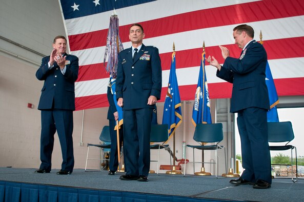 Kentucky's adjutant general, Maj. Gen. Edward W. Tonini (left), and Col. Greg Nelson (right), outgoing commander of the 123rd Airlift Wing, applaud Col. Warren H. Hurst, incoming commander of the wing, during a change-of-command ceremony held in the Fuel Cell Hangar at the Kentucky Air National Guard Base in Louisville, Ky., on Sept. 16, 2012. Hurst is a combat veteran and command pilot with more than 4,000 flying hours. (U.S. Air Force photo by Senior Airman Maxwell Rechel)